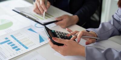 Calculation and Financial Analysis. A business professional using a calculator while discussing data. photo
