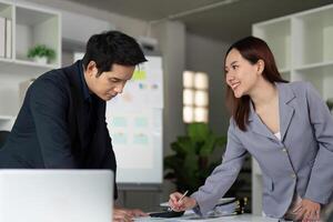 Collaboration and Innovation. Two colleagues discussing project details at a desk in a professional setting. photo