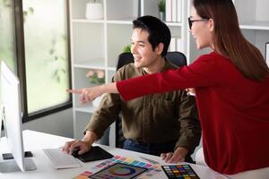 Design Concepts and Color Theory. A designer and colleague discussing vibrant color samples on a computer. photo
