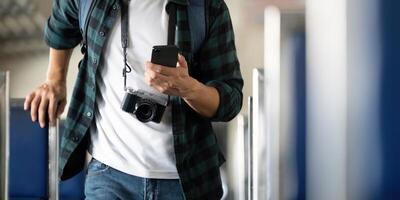 Travel and Photography. A young man with a camera checks his phone while exploring a train. photo