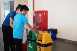 Recycling and Education. A child learns about recycling while disposing of waste properly with the help of a caregiver. photo