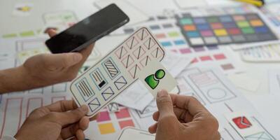 Prototyping and Mobile App Design. Collaborators analyzing wireframes and sketches for a mobile application. photo