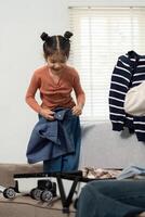 Excitement for Travel and Family Moments. A little girl organizing clothes while packing her suitcase, showcasing joy and anticipation for the upcoming trip. photo