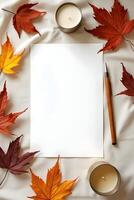 Blank paper with leaves, pen, and a candle on a soft fabric background photo