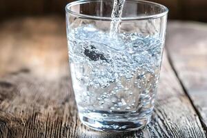 Refreshing Sparkling Water Pouring into Glass on Rustic Wood Table photo
