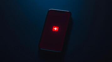 Smartphone Displaying Red Plus Icon in Dark Low Light Setting photo