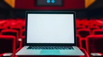 Laptop with Blank Screen in Empty Red Movie Theater Seats photo