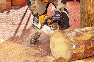 Expert woodworker skillfully cuts into a log using a high-powered chainsaw on a sunny afternoon photo