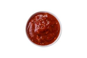 Red sauce or ketchup with spices in ceramic sauce boat photo