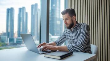 Focused professional working on a laptop with city skyline view from an office workspace. photo