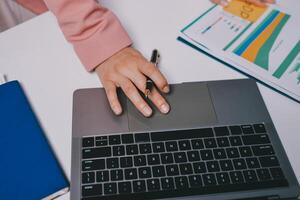 A person is typing on a laptop with a pen and notebook photo