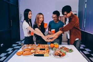 Four people holding hands around a table with food photo