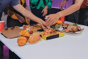 People reaching for food at a table with food photo