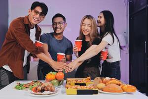 Four people holding hands while standing around a table with food photo
