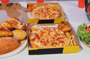 A table with two boxes of pizza and a salad photo