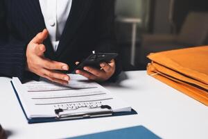 A person in a suit holding a cell phone and looking at a document photo