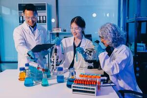 Three people in lab coats looking at something on a tablet photo
