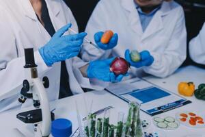 Three people in lab coats and gloves are working on vegetables photo