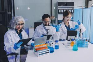Three people in lab coats working on a computer photo