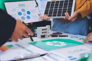 People working on a table with a solar panel and paper photo