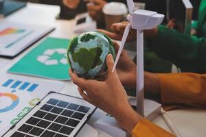 The earth is being held by a person's hand in front of a laptop photo
