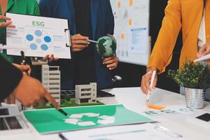 People working together on a table with a green building photo