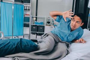 A man in a hospital bed with his hands up photo