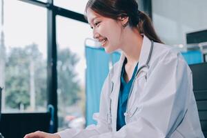 A woman in a lab coat is smiling while using a laptop photo