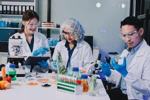 Three people in lab coats working on a tablet photo