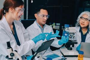 Three people in lab coats looking at a laptop photo