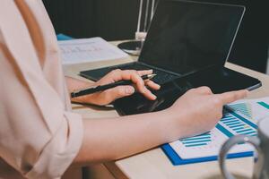 A person is using a tablet and pen on a desk photo