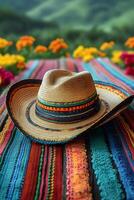 Authentic Mexican sombrero resting on a rustic wooden table with bright textile patterns in the background photo