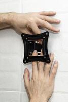 man holding a TV bracket against the wall photo