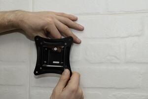 A man tries on a white wall mount bracket, close up photo