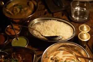 table covered with Indian dishes, rice in a plate close-up photo