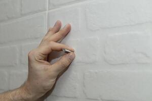 A man's hand with a screw for mounting near the wall. photo