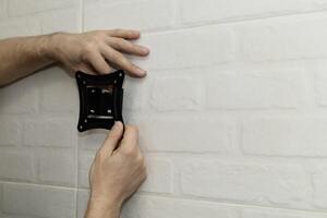 A man tries on a white wall mount bracket photo