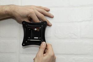 A man tries on a mount bracket and screw photo