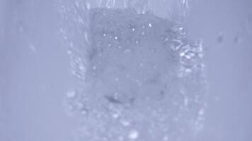 Experience the captivating moments of an ice cube splashing into water, showcasing dynamic liquid motion video