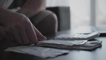 A person reviews bills and financial papers on a desk near a computer, highlighting personal finance. video