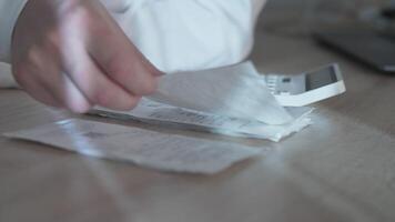 A person meticulously analyzing and calculating various expenses using receipts and a calculator placed on a desk video