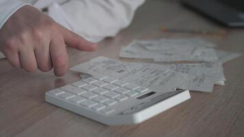 A person diligently using a calculator to effectively manage their finances, surrounded by numerous receipts on a desk video