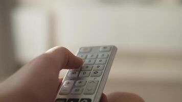 A hand carefully pressing buttons on a remote control, capturing a warm and intimate moment of technology use video