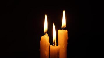 Three beautifully lit candles are creating a tranquil and serene atmosphere against a contrasting dark backdrop video