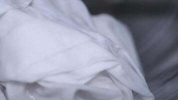 Closeup of white laundry in a washing machine, showing soap bubbles and fabric movement during washing video