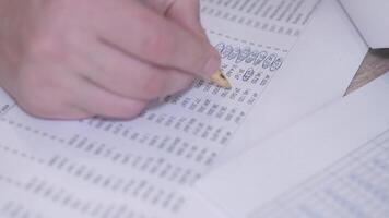 A detailed closeup of data analysis displaying a hand carefully marking important numbers on a document with a pen video