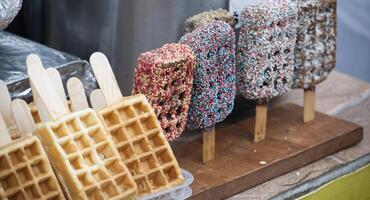 Assorted waffle and chocolate pops on sticks, arranged on a rustic wooden display photo