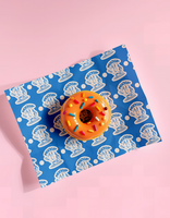 A colorful donut rests on blue and white patterned wrapping paper psd