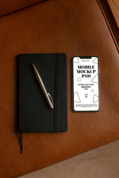 Mobile mockup with a notebook and pen on a leather surface. psd