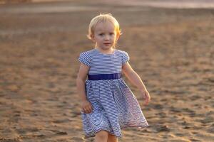Young child exploring sandy beach during golden hour, showcasing innocence and joy in a serene environment photo